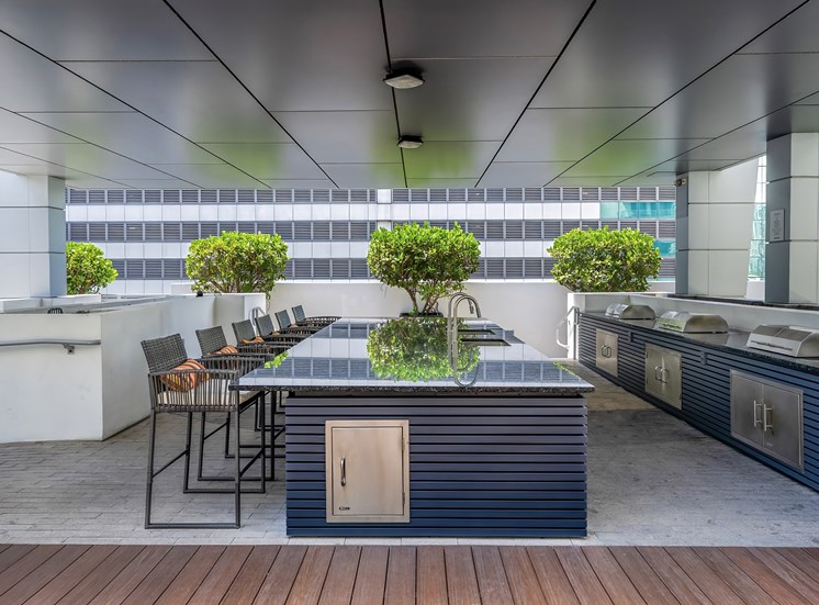 A modern outdoor kitchen with a bar and chairs.